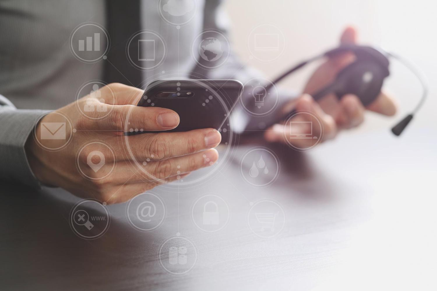 caption: Businessman using VoIP headset with mobile phone and concept communication call center.