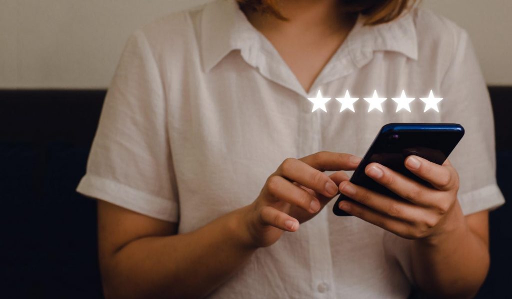 image 3caption: Woman sitting using smartphone and giving a five-star symbol to boost business concept score. 