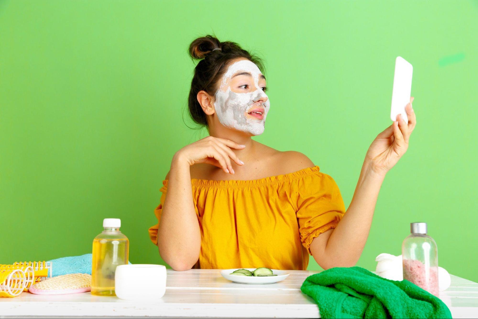 A woman wearing a skin-nourishing mask and holding a mobile phone.